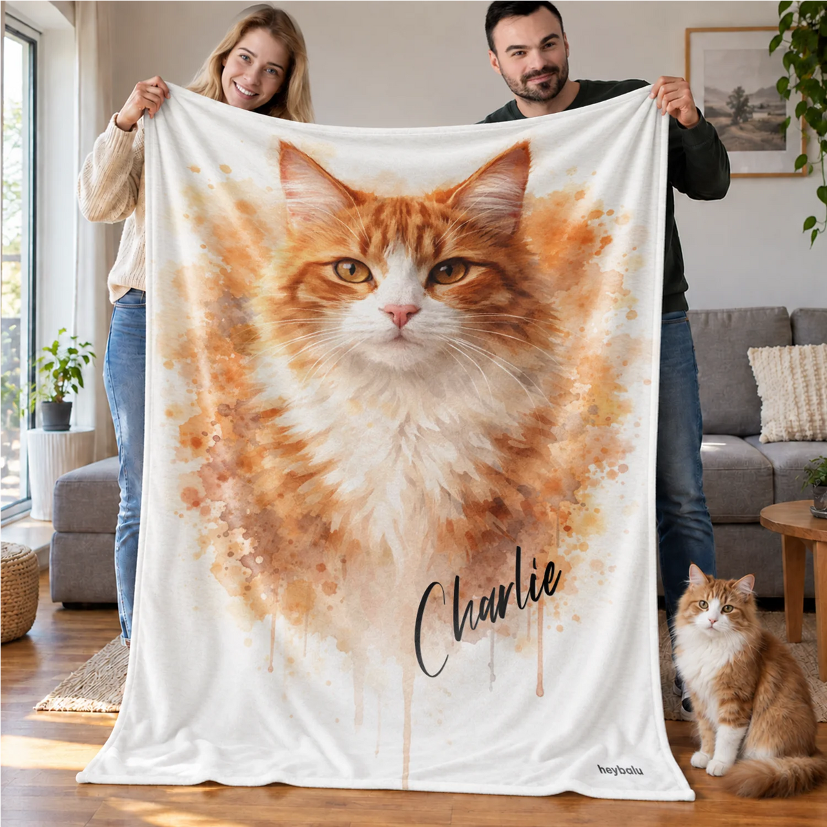 Paar hält die Aquarell-Katzendecke mit rot-weißer Katze, daneben die echte Katze