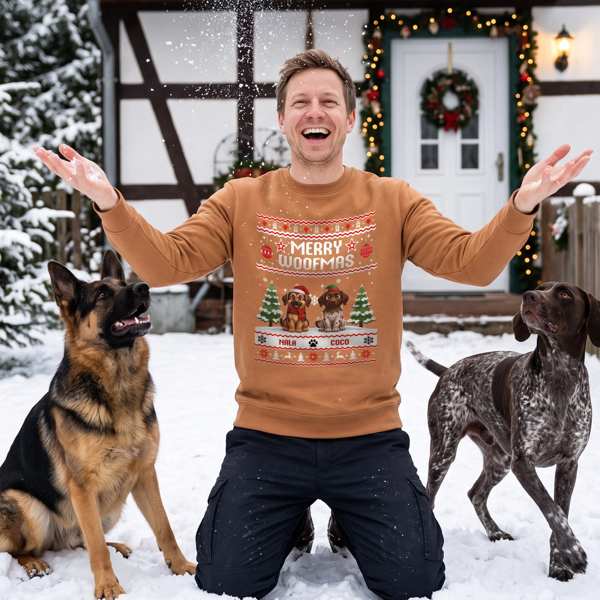 Mann im Merry-Woofmas-Pullover mit zwei Hunden im Schnee