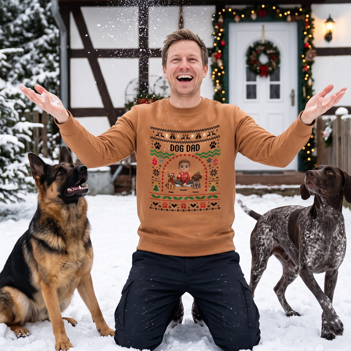 Mann im beigen Sweater mit Schriftzug Dog Dad und zwei Hunden im Schnee