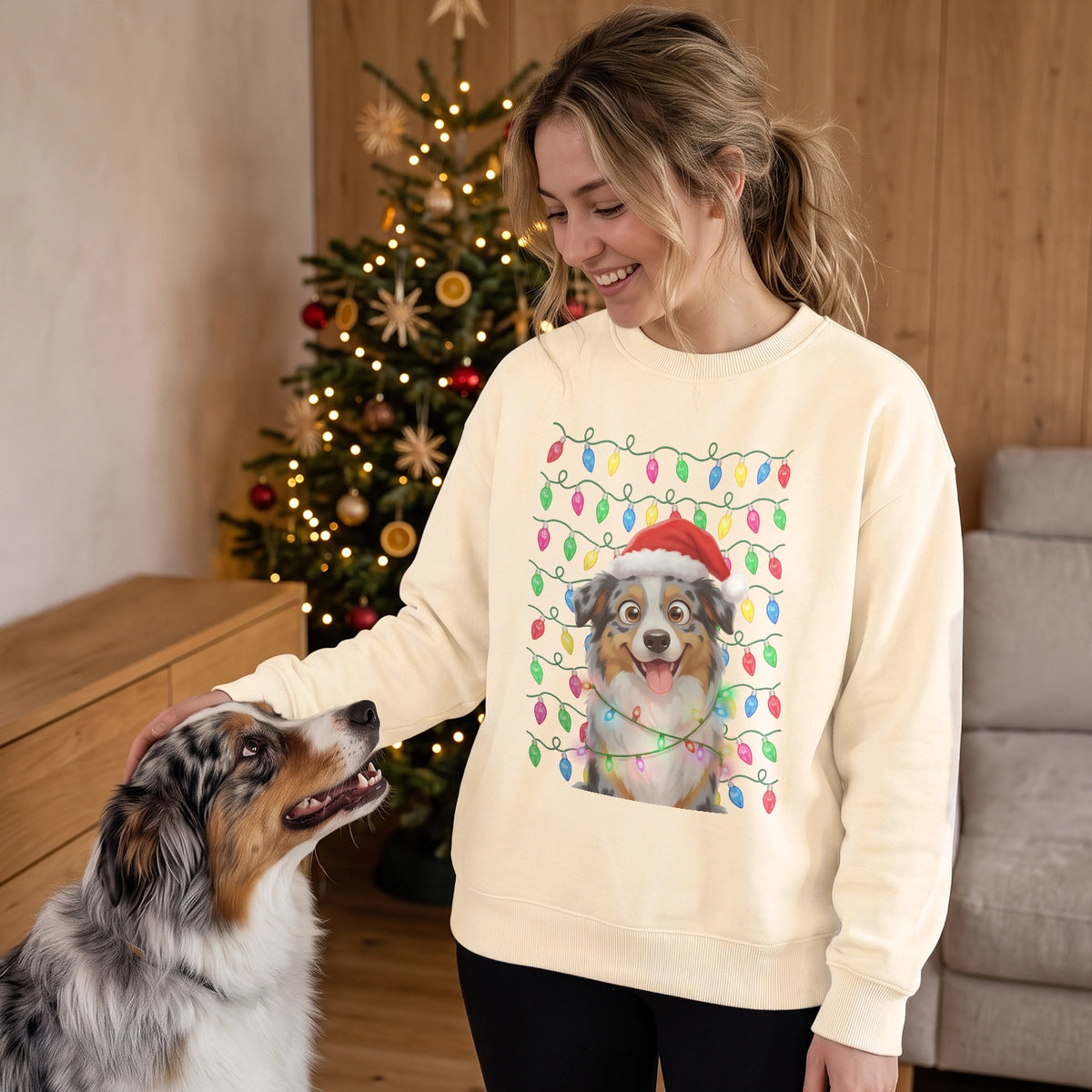 Frau im vanillefarbenen Pullover mit Australian Shepherd als Cartoon vor dem Weihnachtsbaum
