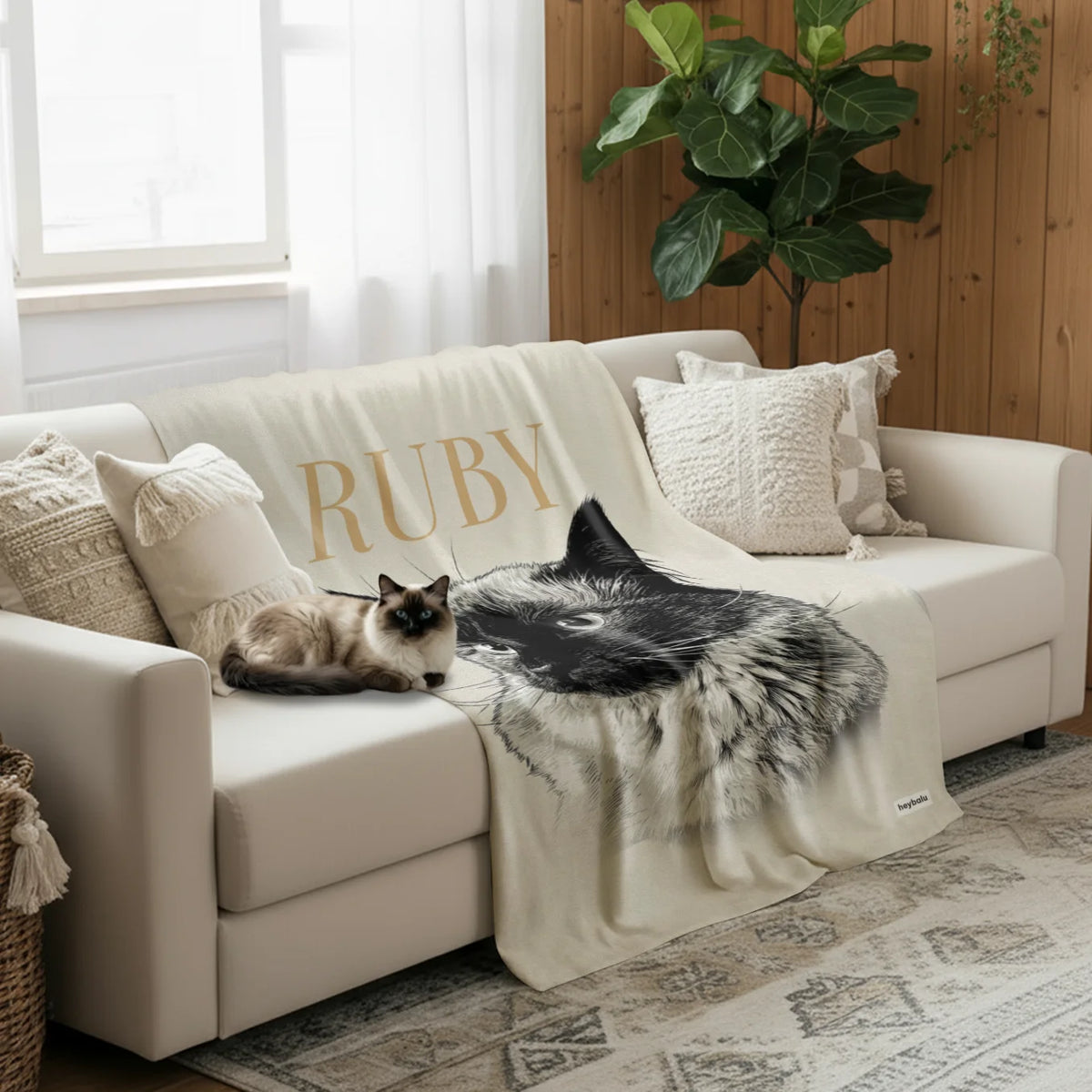 Siamkatze liegt neben der cremefarbenen Retro-Katze-Decke auf dem Sofa